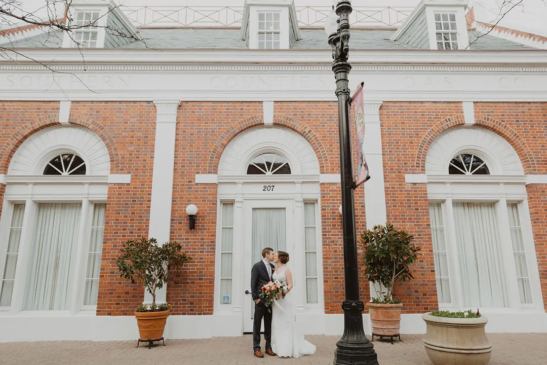 Couple kissing outside an arched brick facade