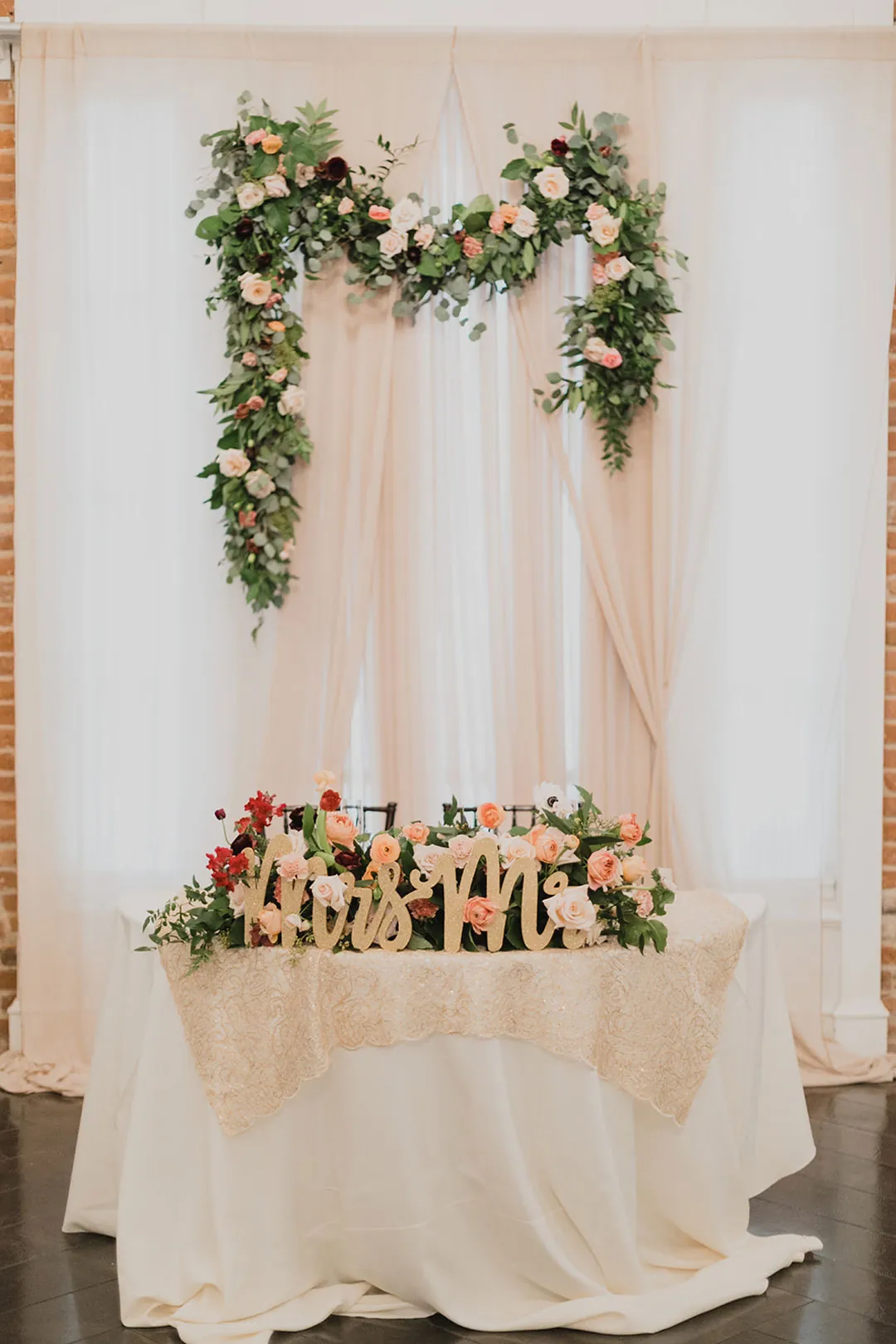 Sweetheart table in front of a pink floral backdrop