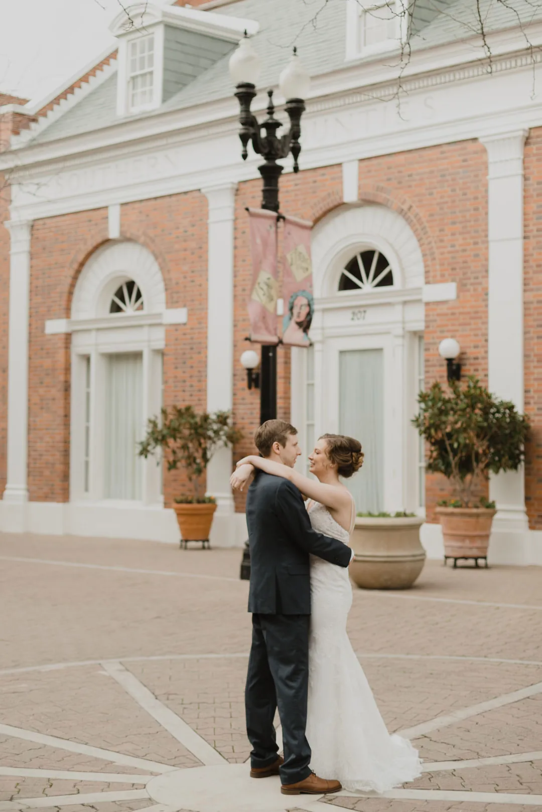 Couple kissing outside an arched window in a brick building