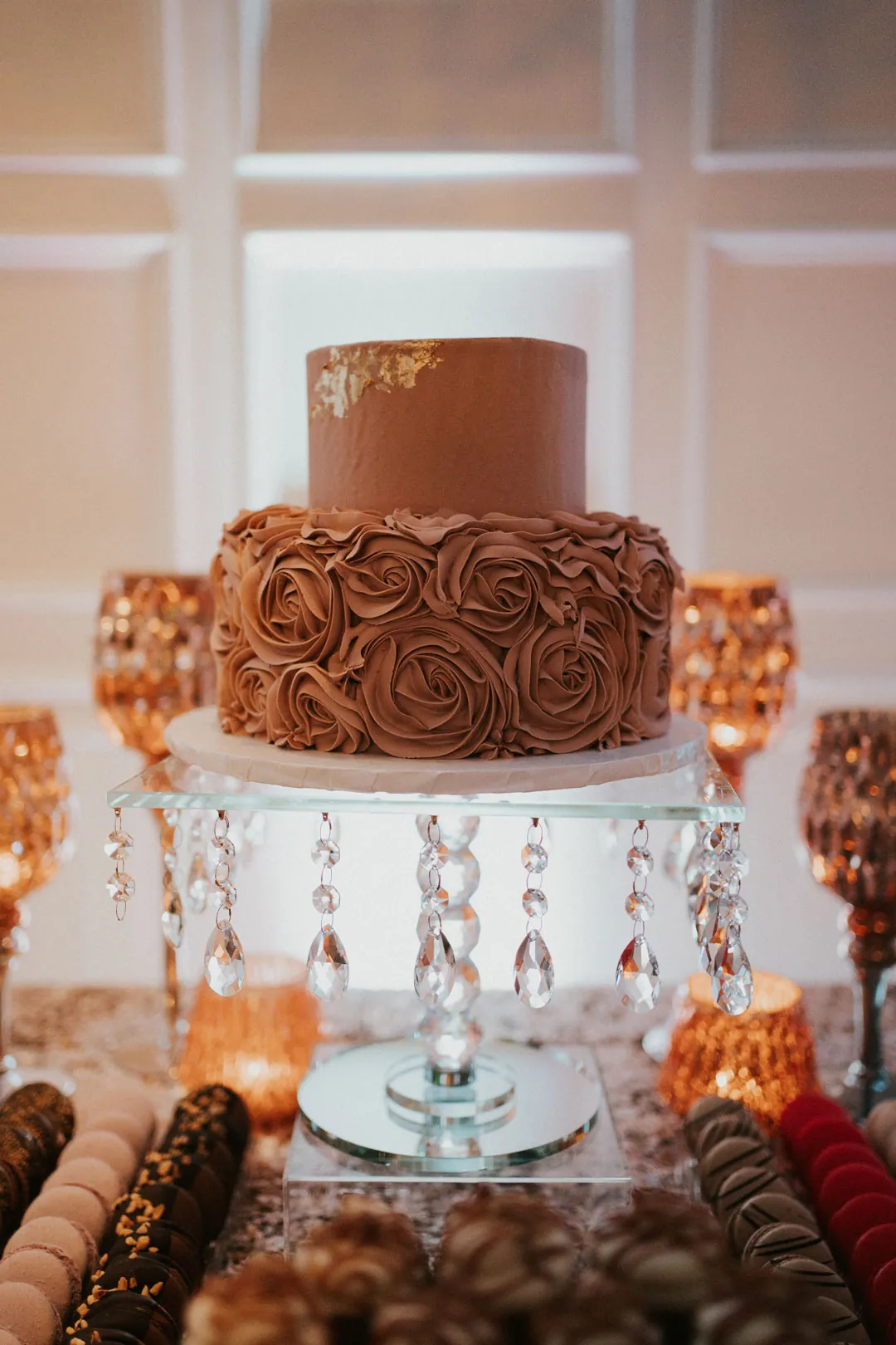 Chocolate-frosted tiered cake on a glass stand