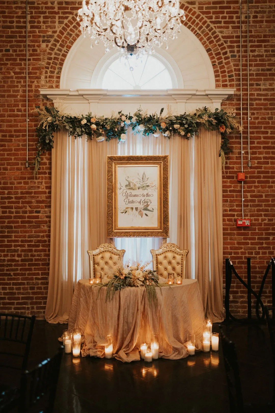 Candlelit sweetheart table beneath a floral arch