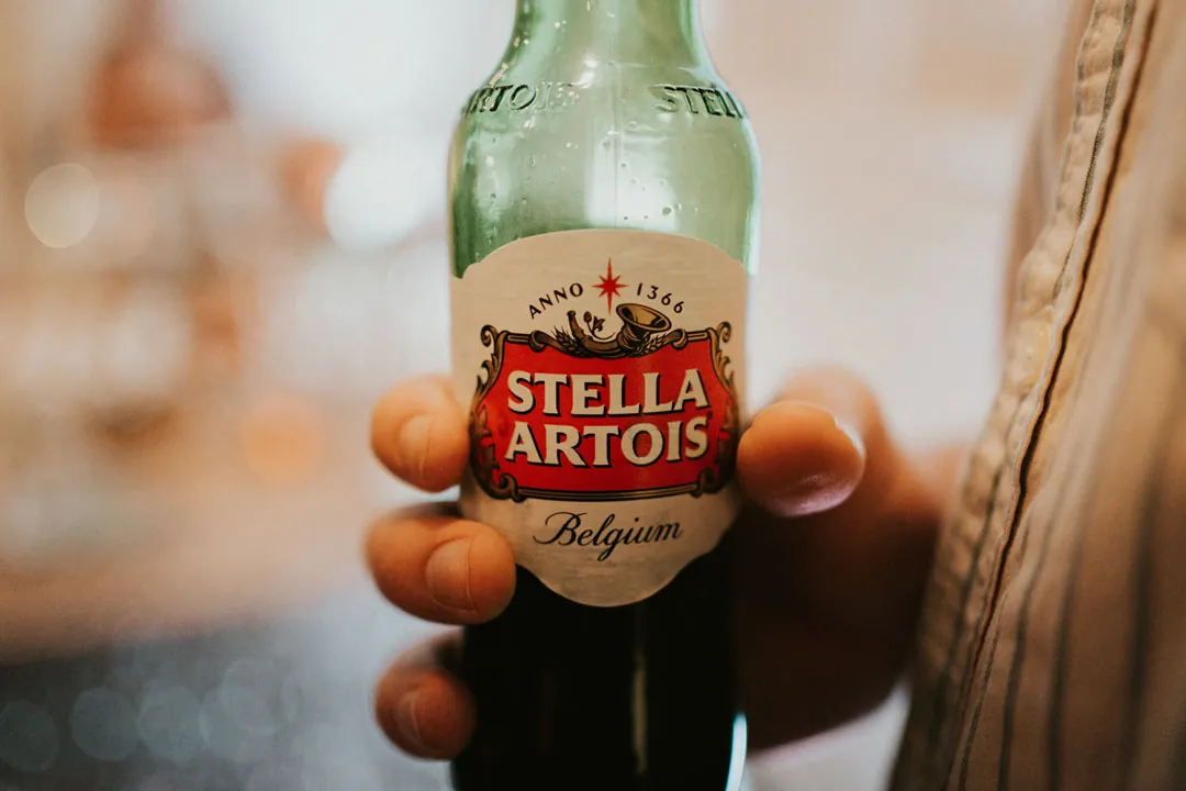 A hand holding a Stella Artois beer bottle