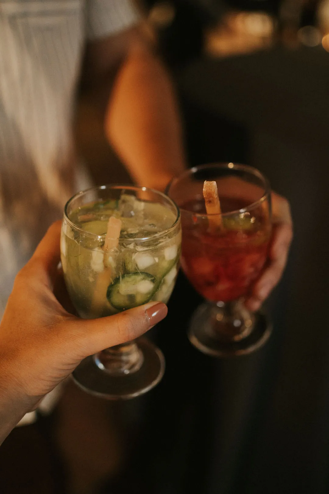 Two guests holding colorful cocktails