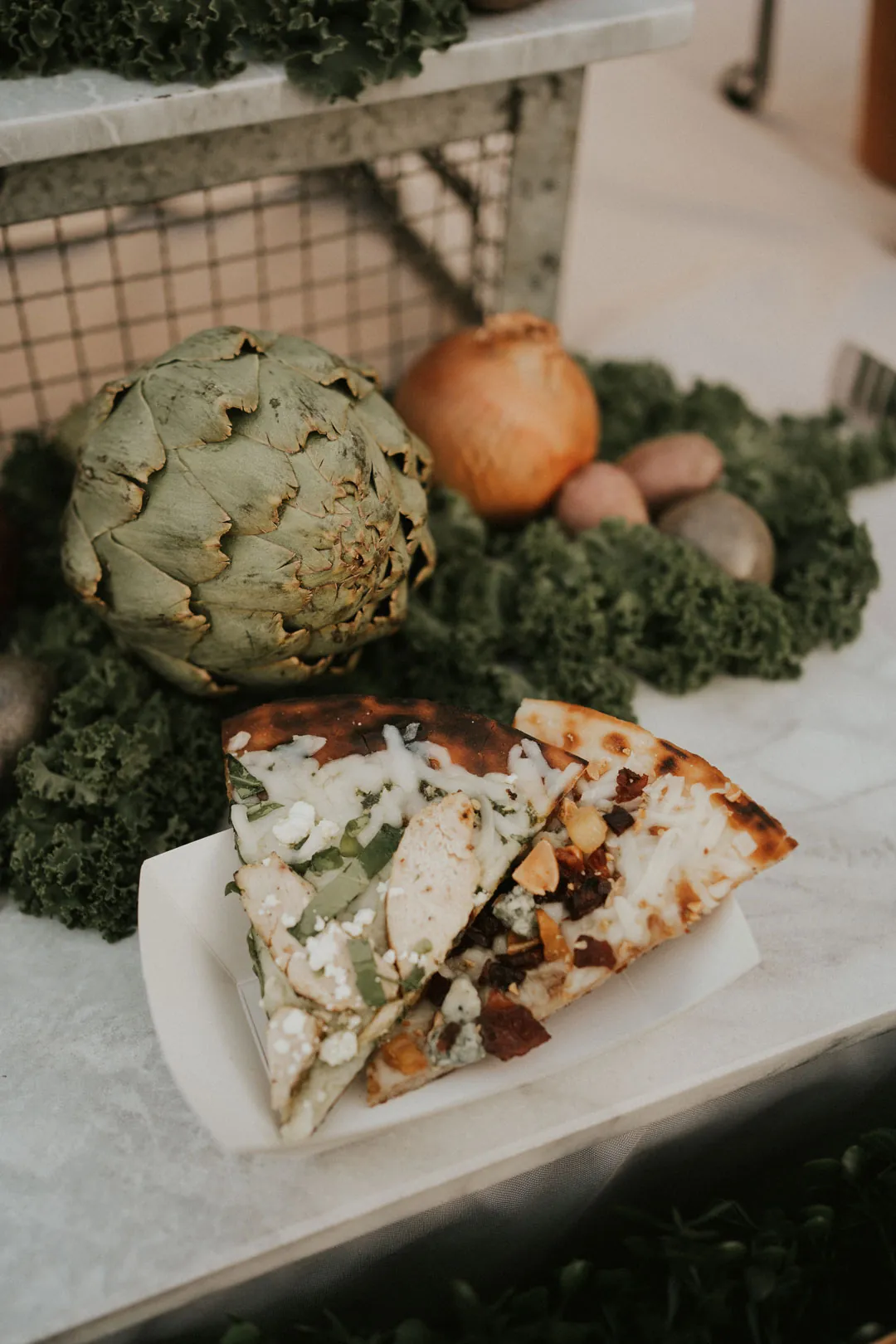 A small plated dish beside artichokes and vegetables