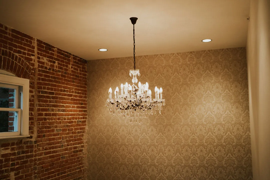 Chandelier hanging beside exposed brick and patterned walls