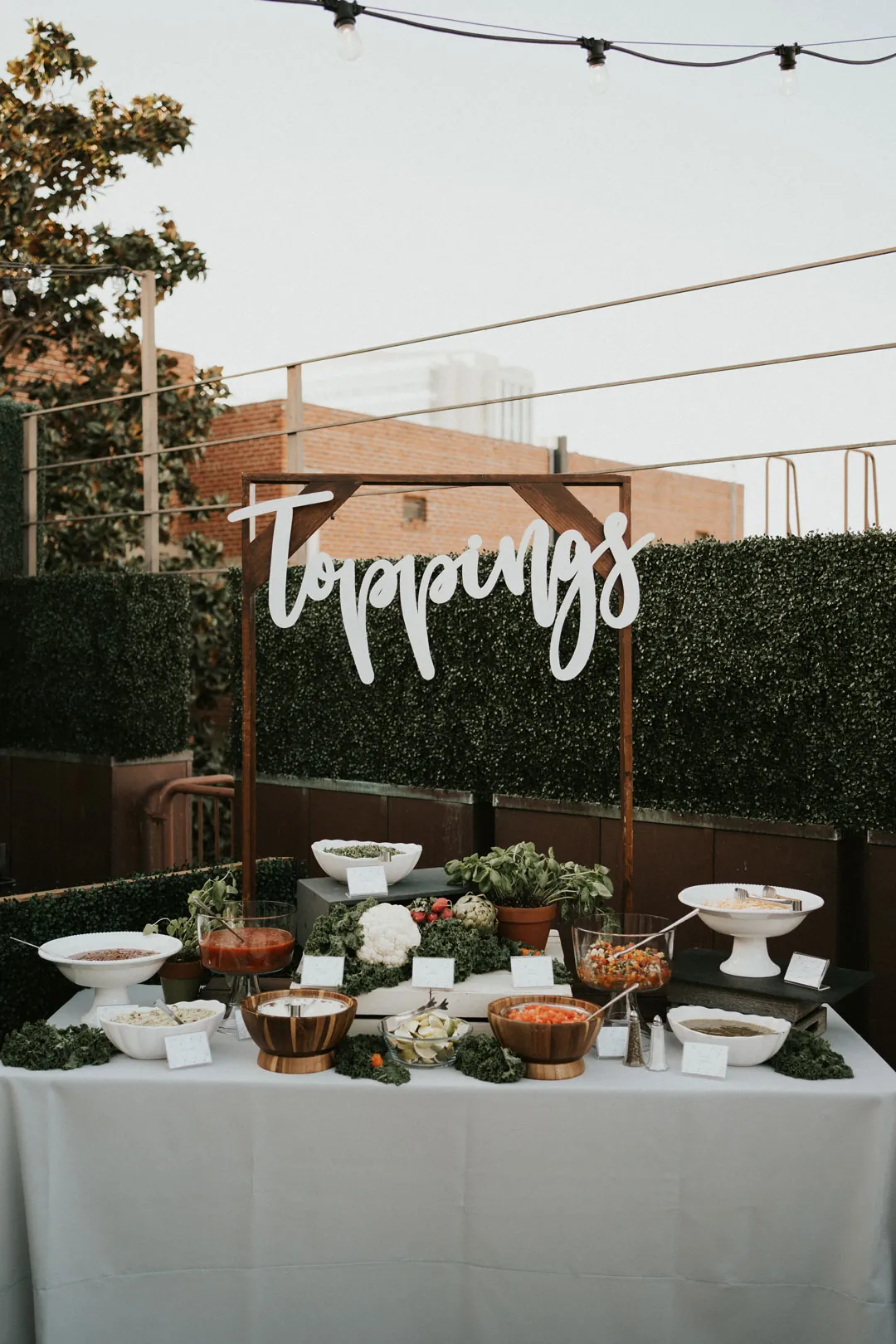 Outdoor food station beneath a Toppings sign