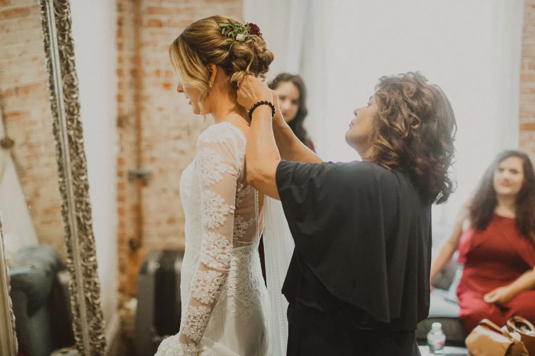 Attendant fastening the back of a bride's dress