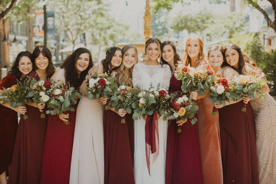 Bride and bridesmaids holding red and green bouquets
