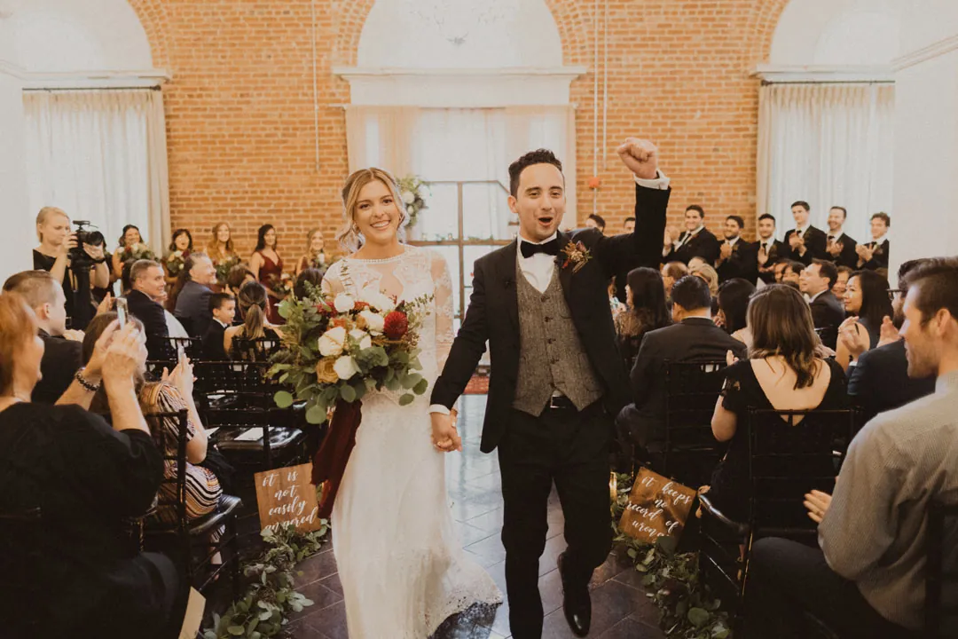 Newlyweds walking down the aisle as guests applaud