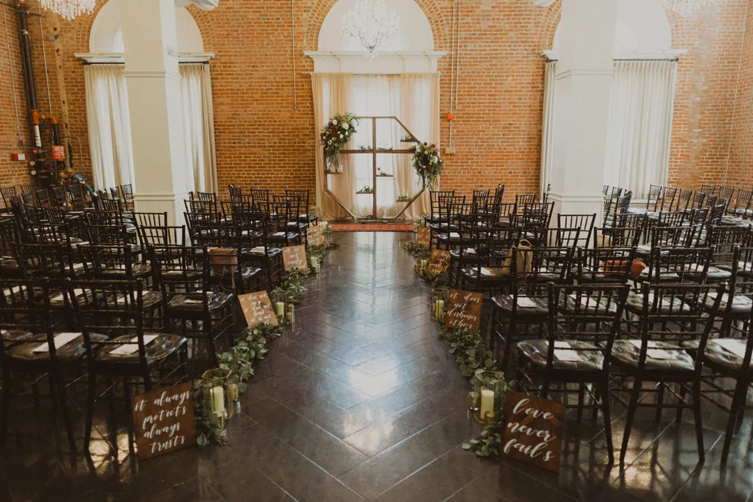 Rows of black ceremony chairs facing a floral arch