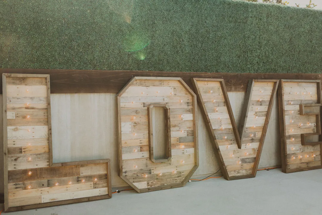 Large wooden letters spelling LOVE against a greenery wall