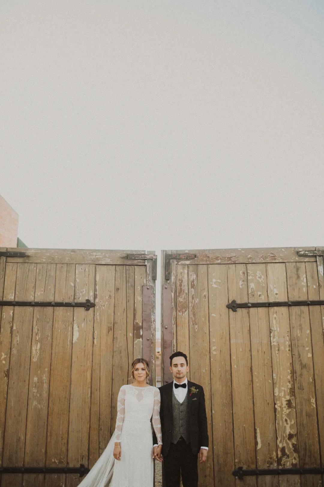 Couple standing together before tall wooden doors