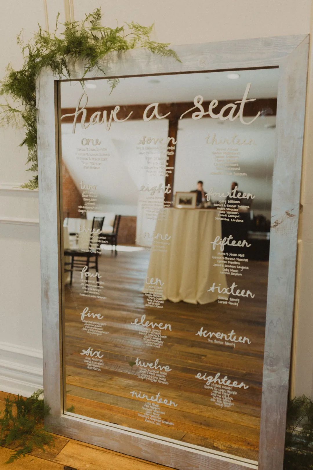 Mirrored seating chart decorated with greenery