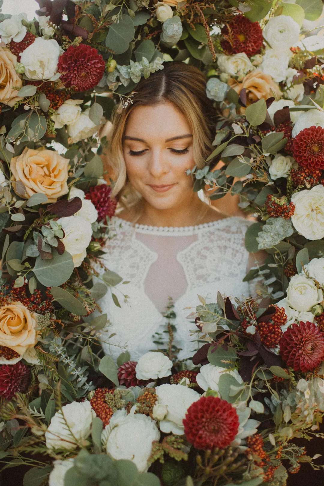 Bride holding a bouquet in front of a floral arrangement