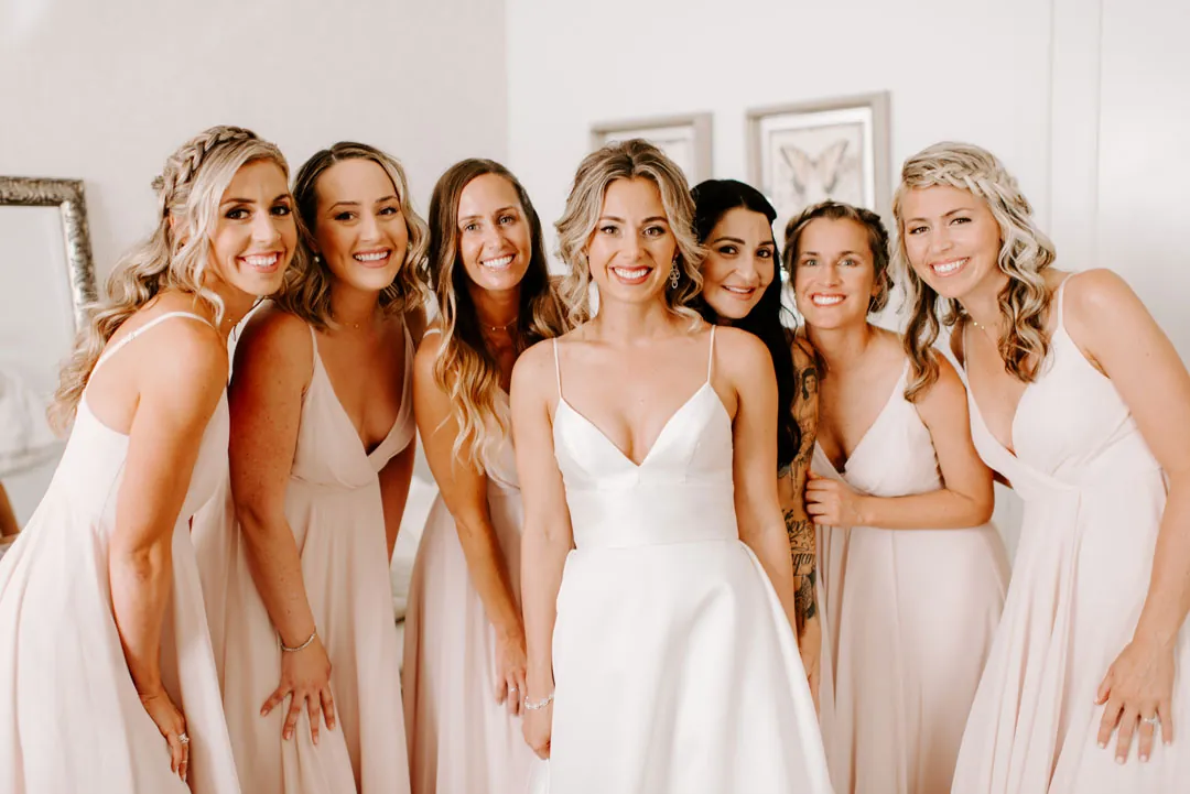 Bride posing with bridesmaids in pale pink dresses