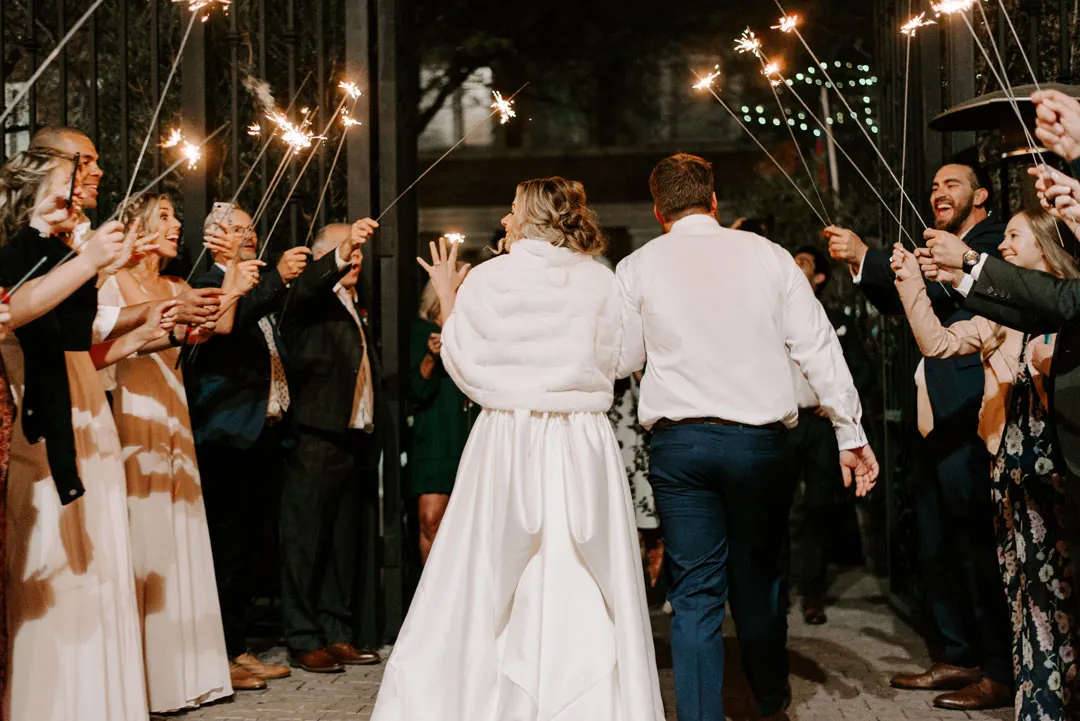 Guests waving sparklers around the newlyweds