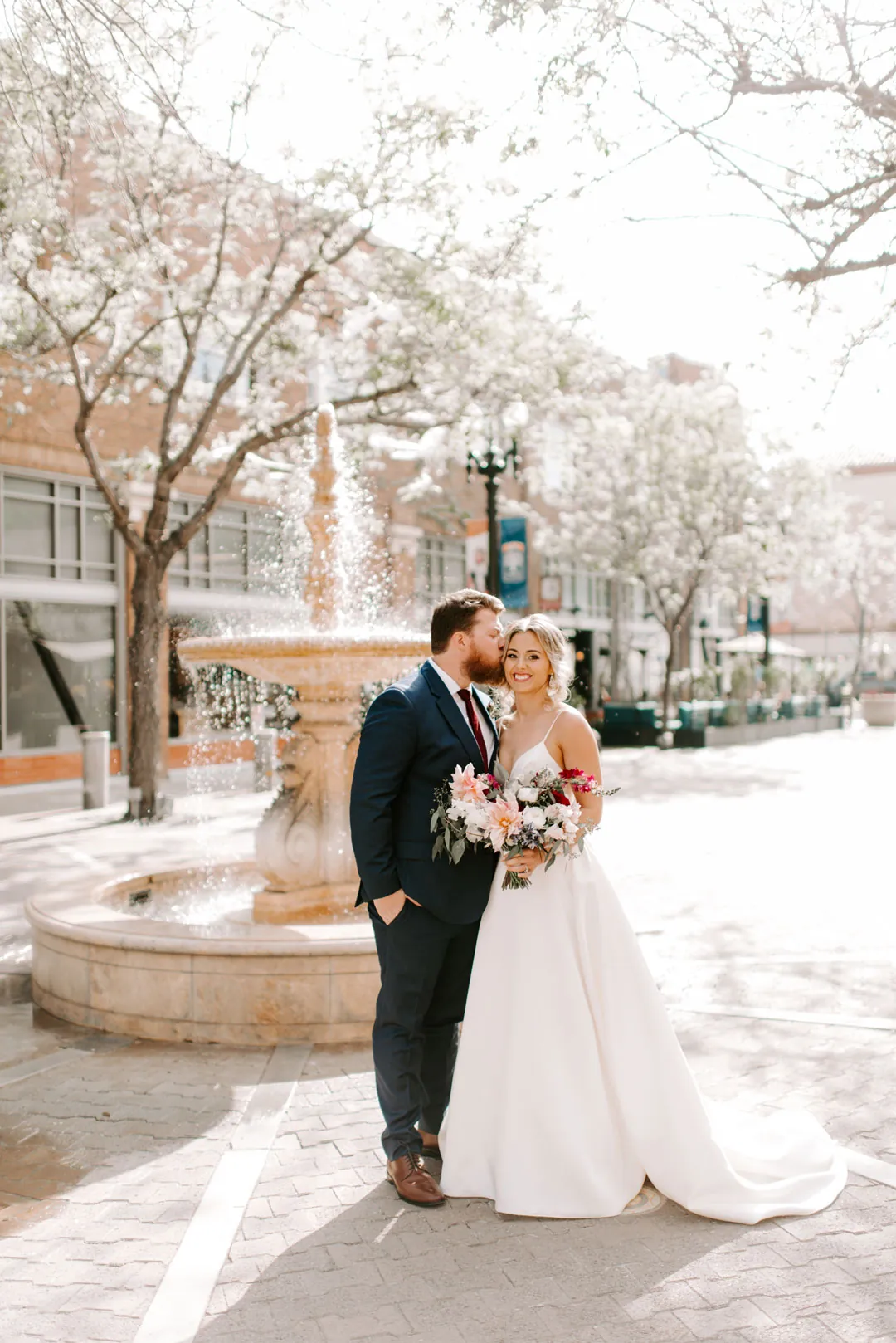 Bride and groom embracing beside an outdoor fountain