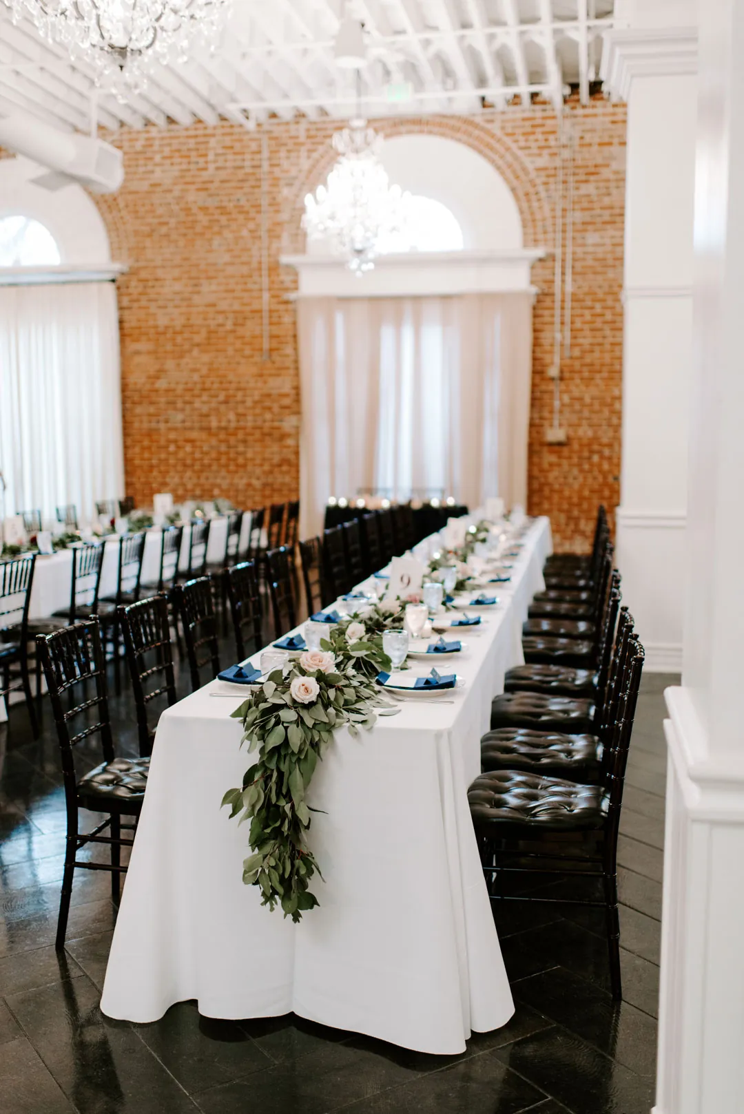 Long reception table beneath chandeliers