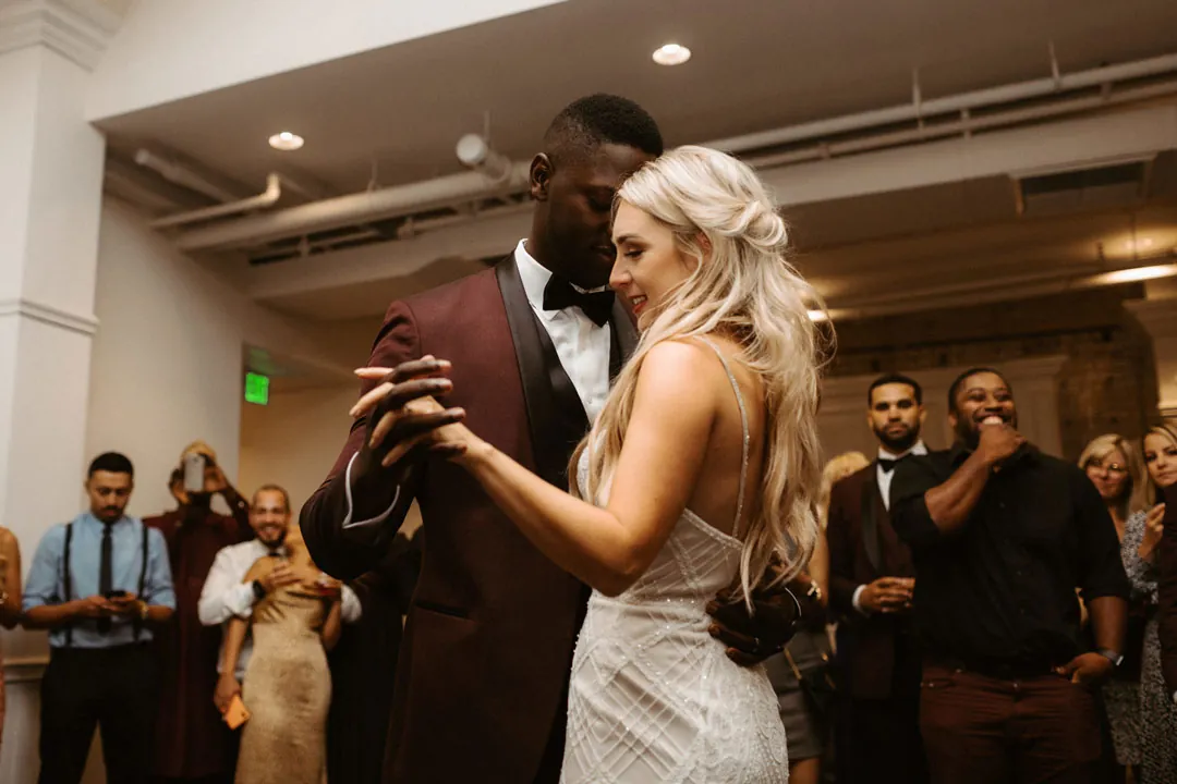 Bride and groom dancing as guests look on