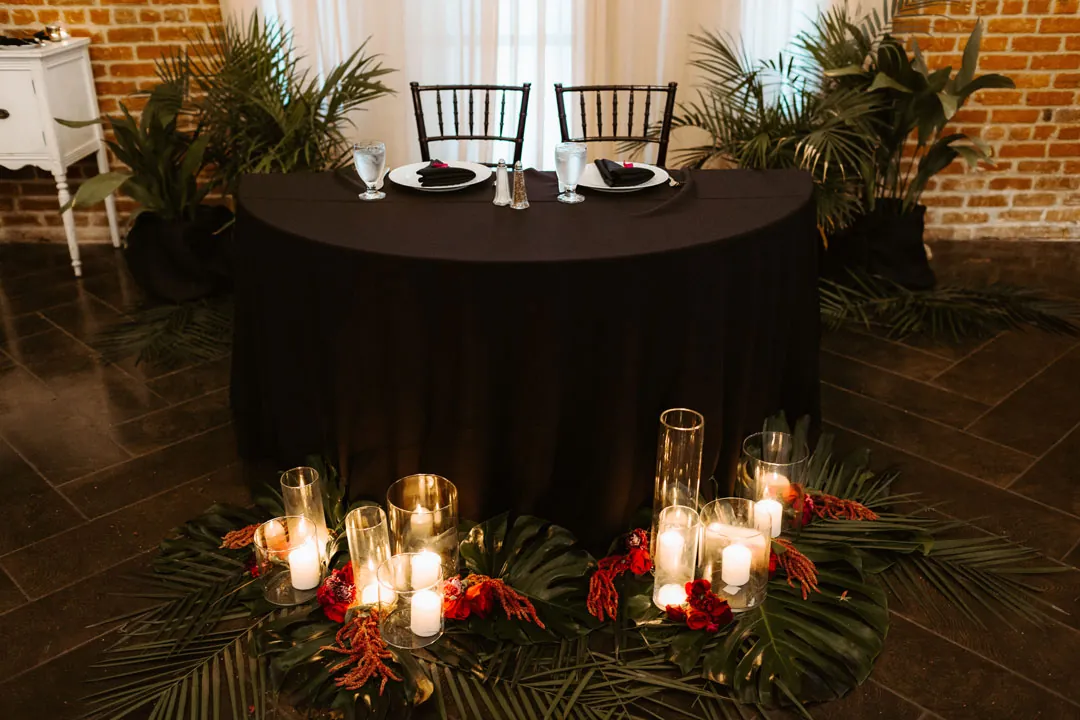 Round sweetheart table with candles and red flowers
