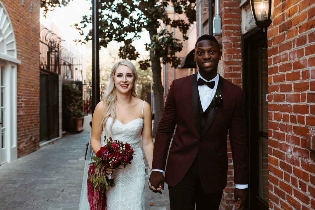 Newlyweds walking hand in hand on a sidewalk