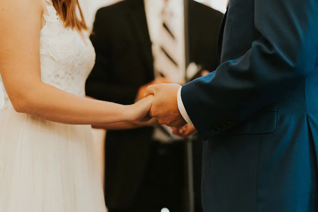 Couple hold hands during their wedding ceremony.