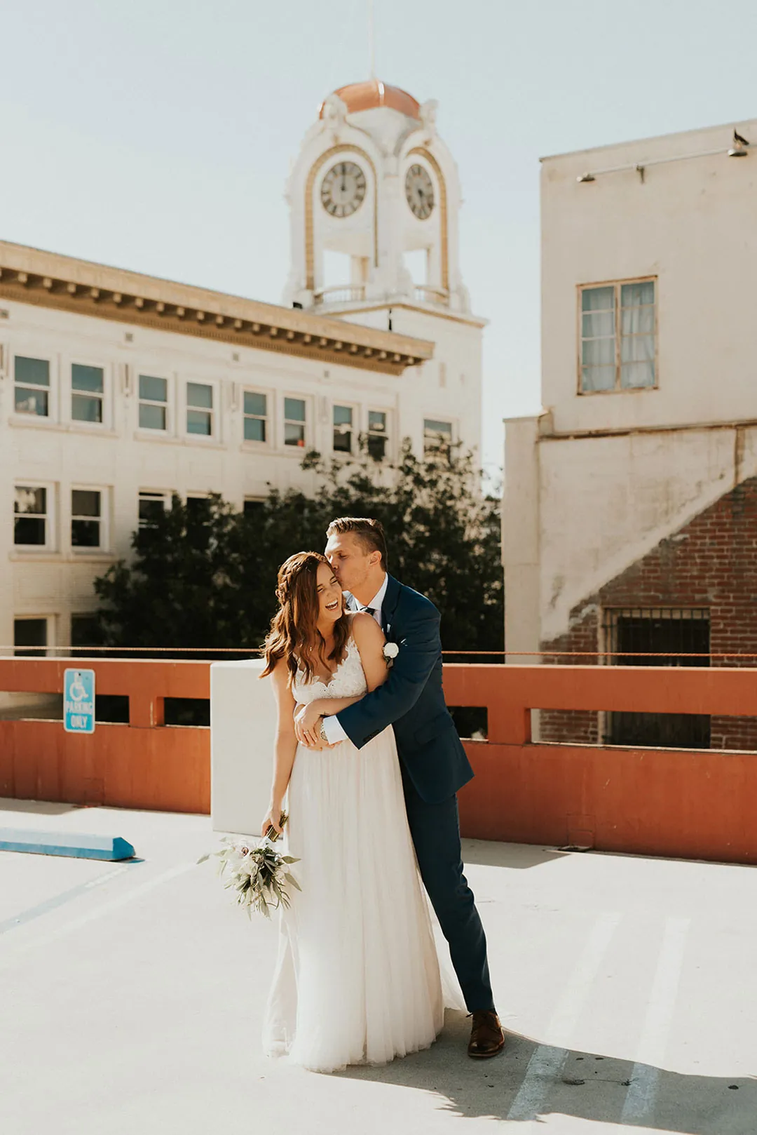 Couple kiss on a sunlit rooftop terrace.