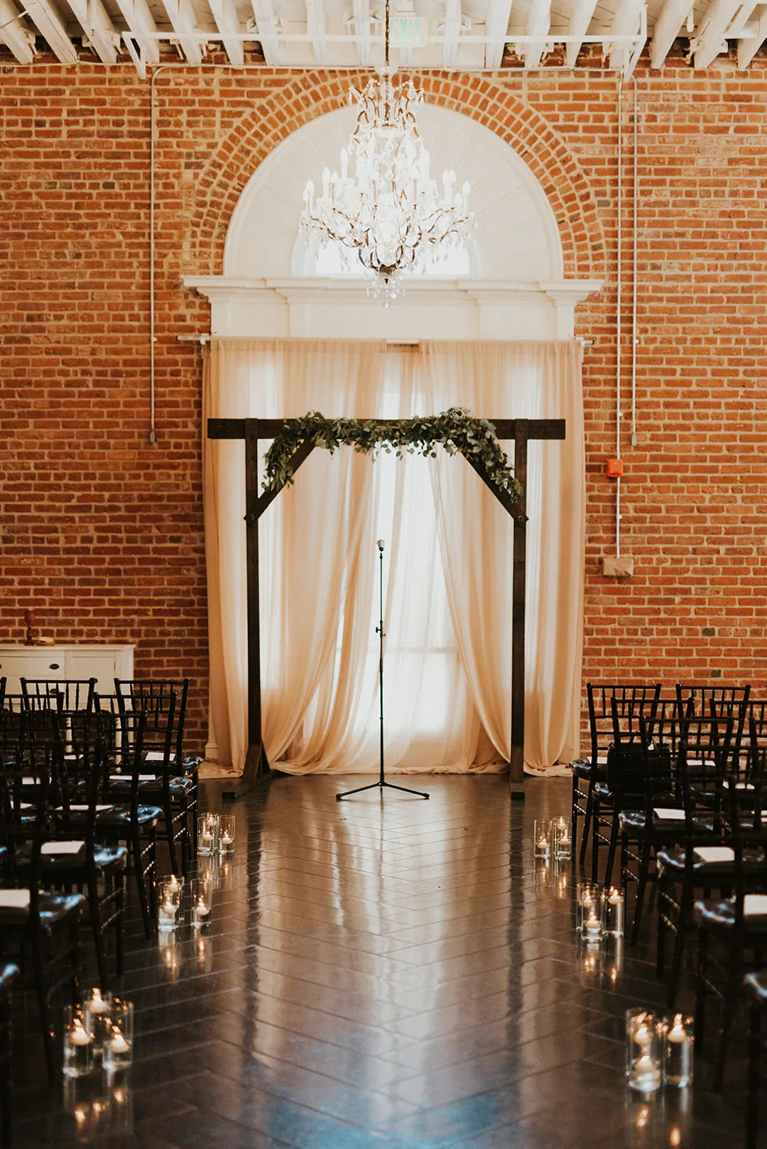 Geometric ceremony backdrop beneath an arched ballroom window.
