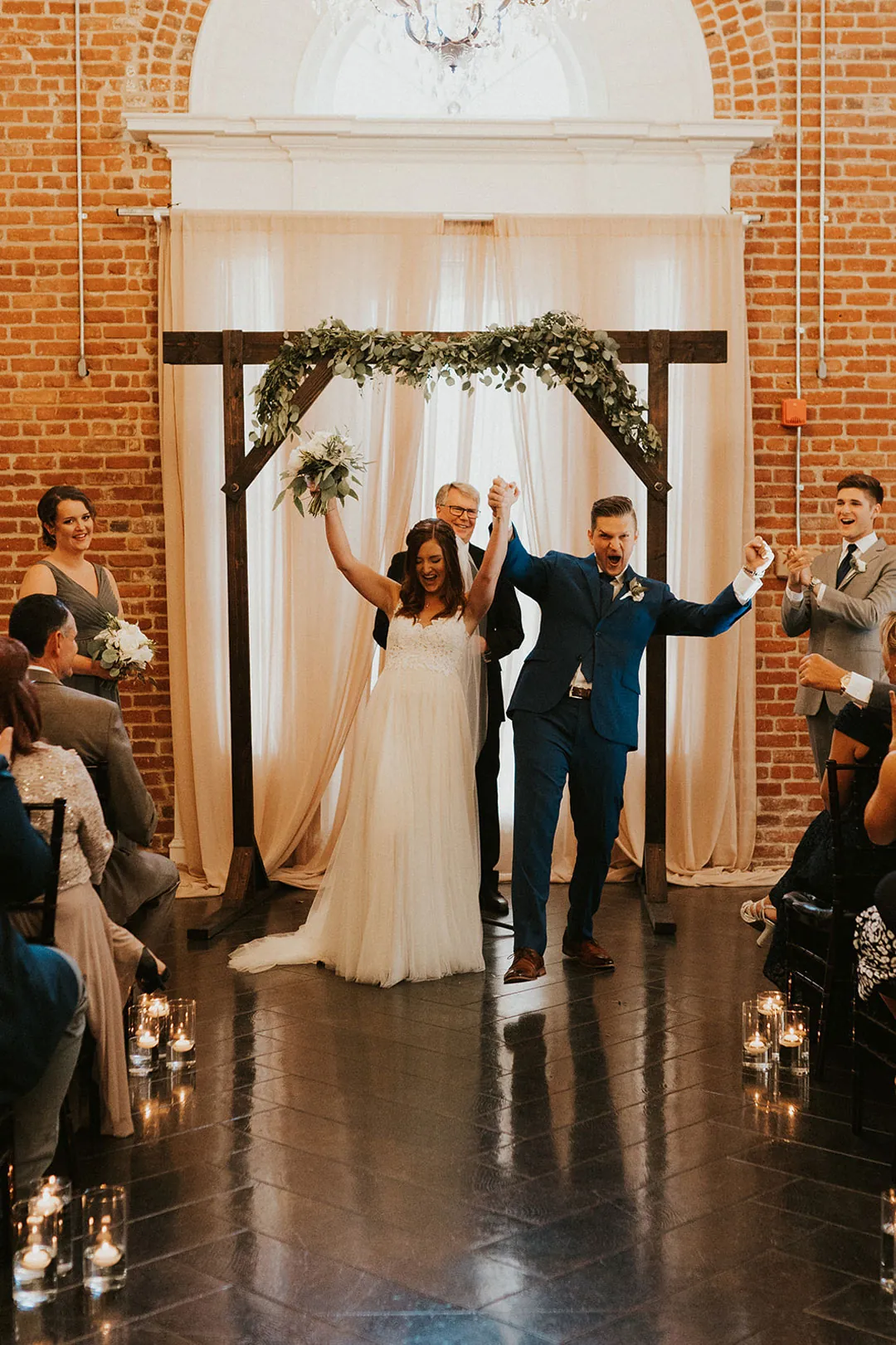 Newlyweds raise joined hands at the end of the aisle.