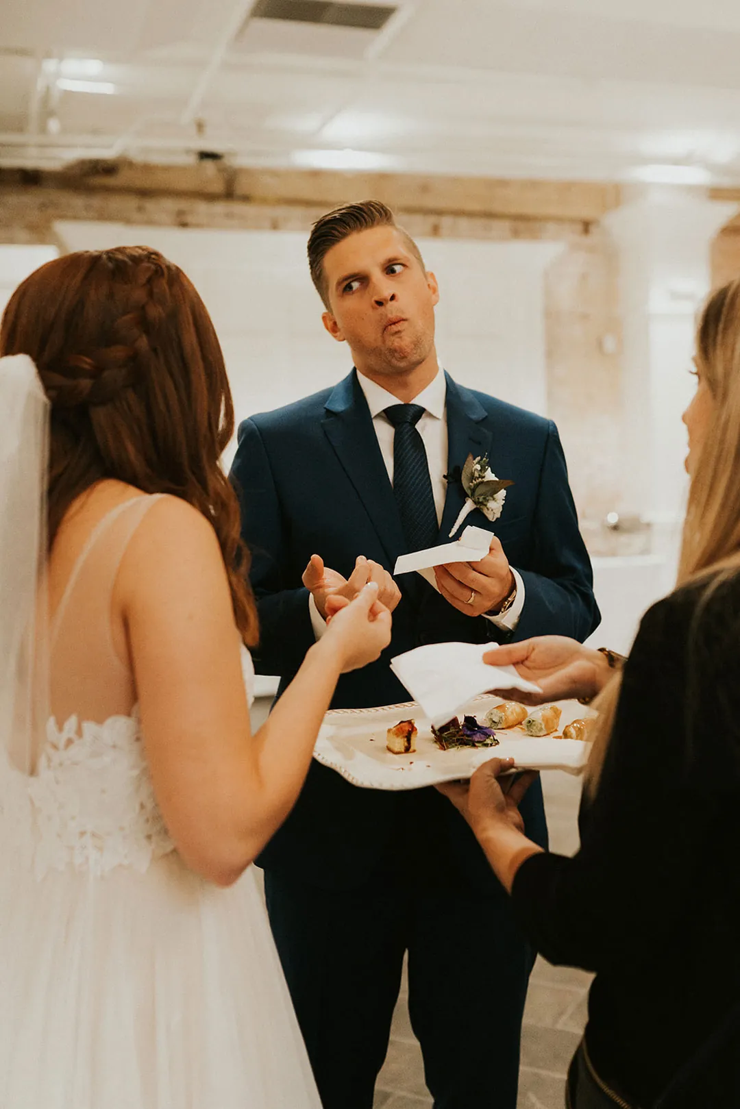 Groom talks with guests while holding a plate of food.