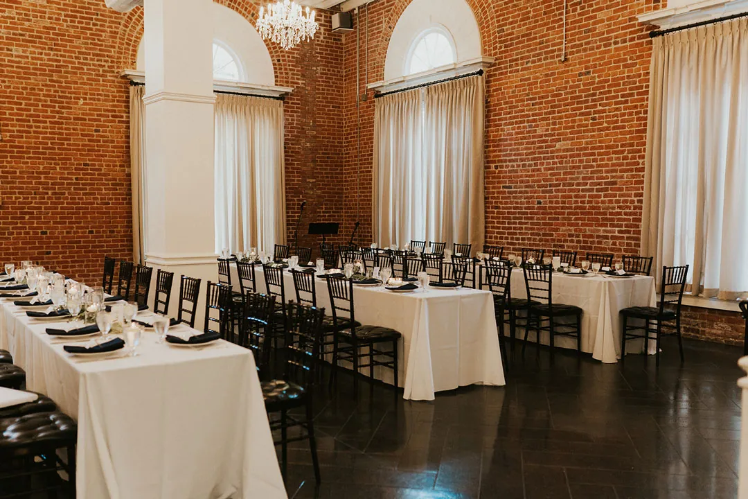 Long reception tables set against exposed brick.