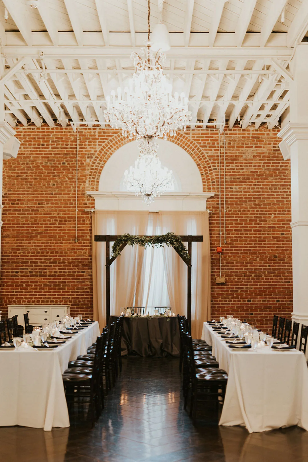 Long reception tables flank a chandelier lit ballroom aisle.