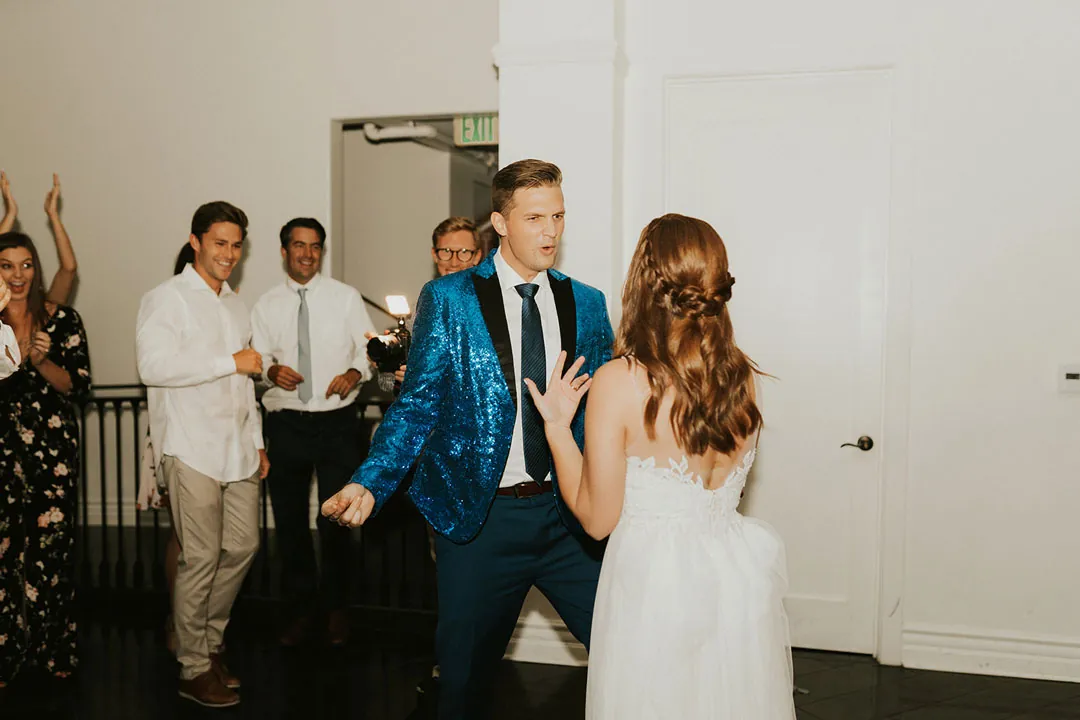Newlyweds dance with guests watching behind them.