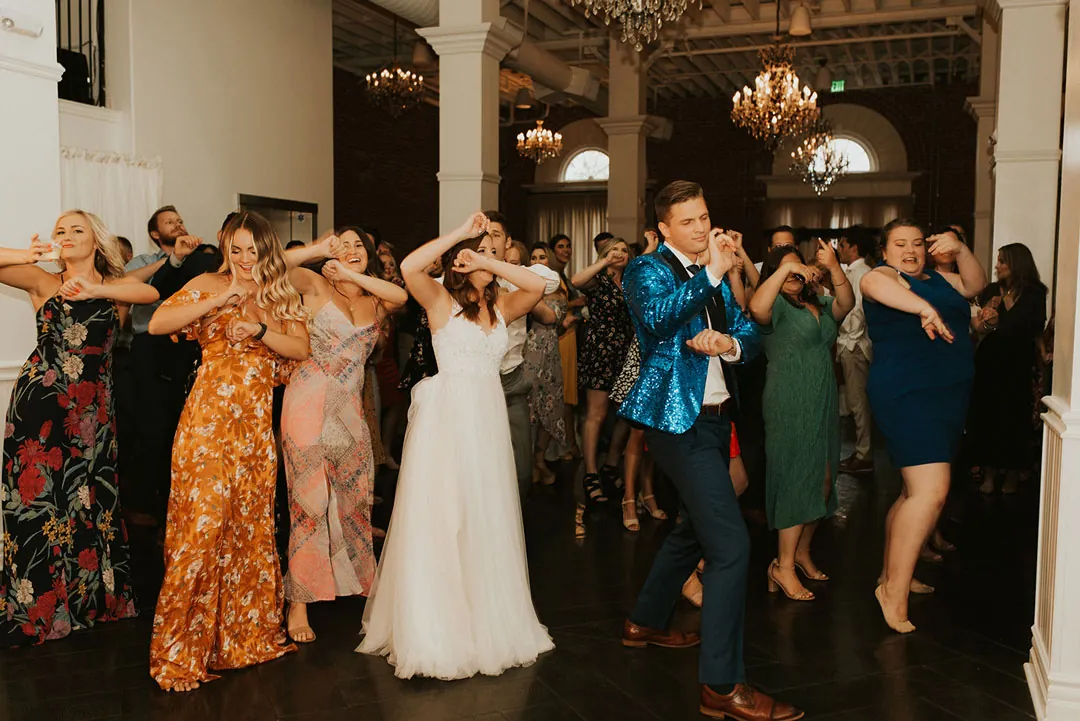 Bride and guests dance together with raised hands.