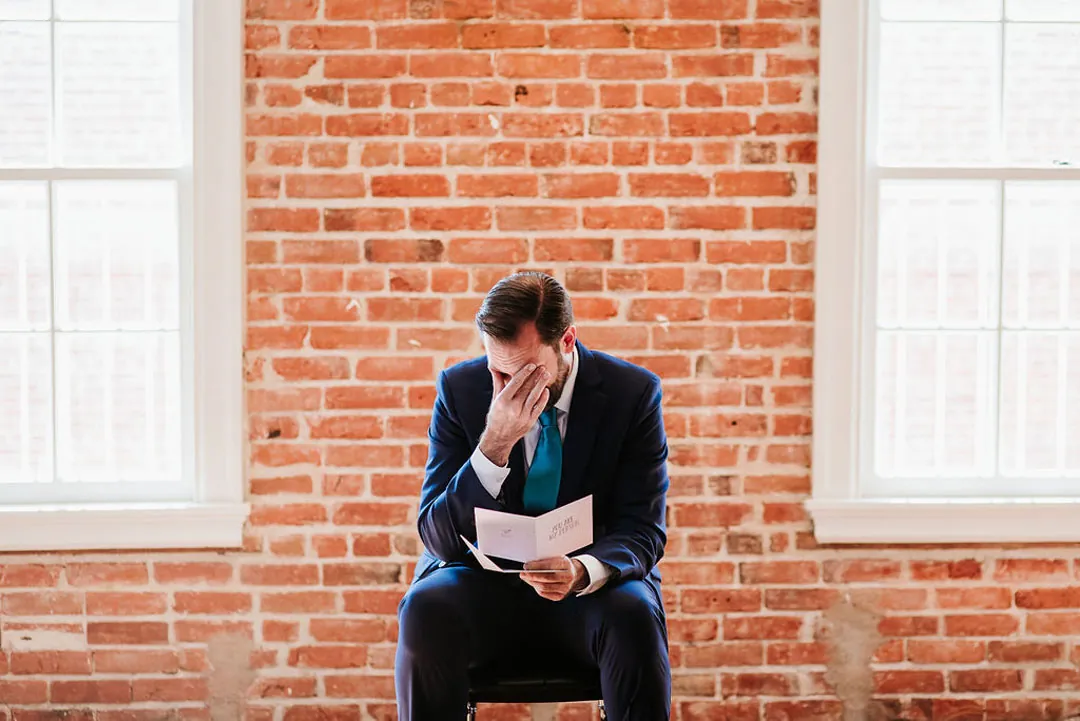 Groom wipes his face while reading a note.