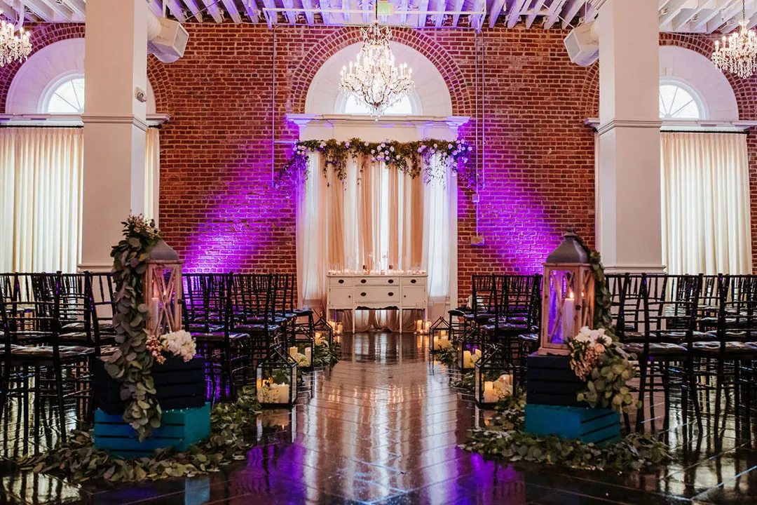 Purple lighting illuminates the floral ceremony backdrop.