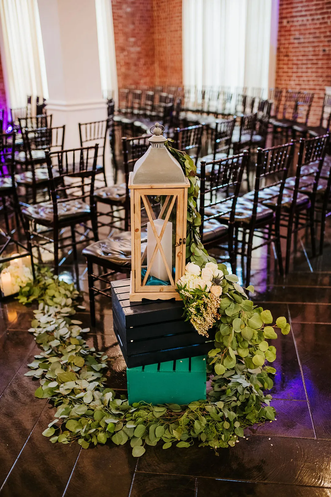 Lantern and greenery decorate the end of the ceremony aisle.