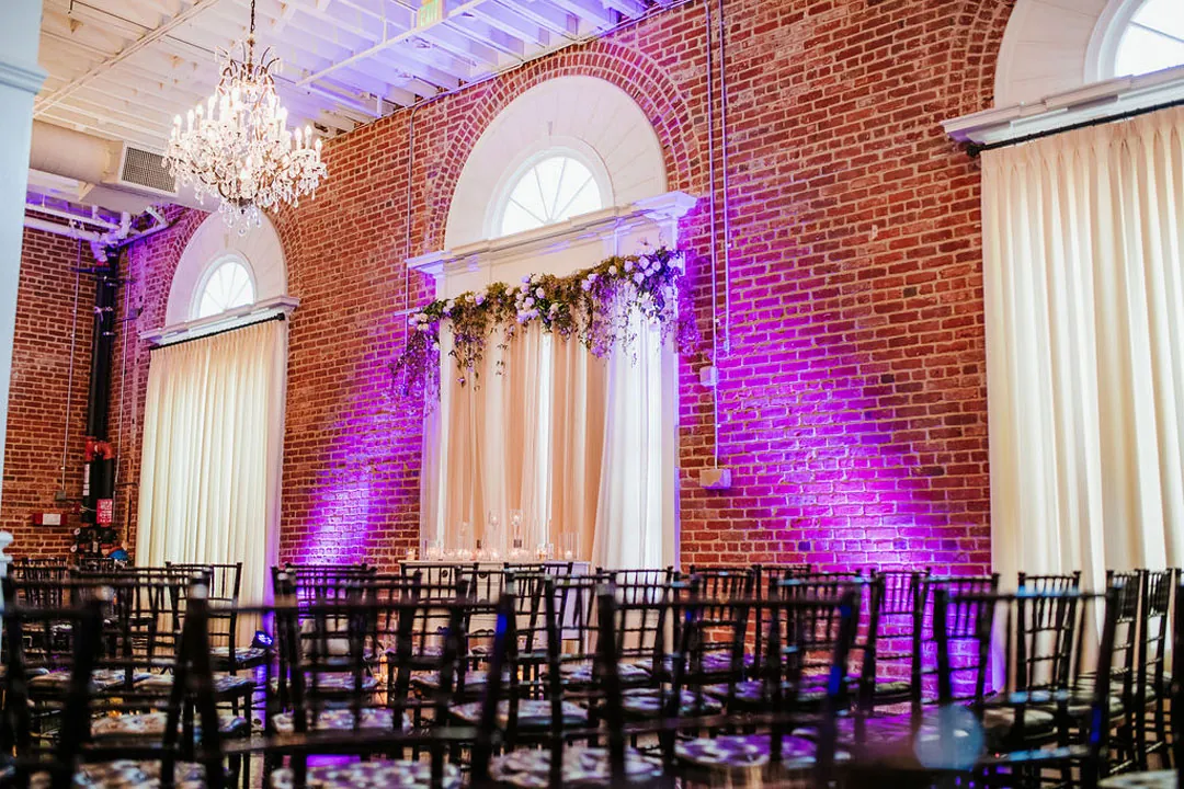 Purple lights illuminate a draped ceremony backdrop.
