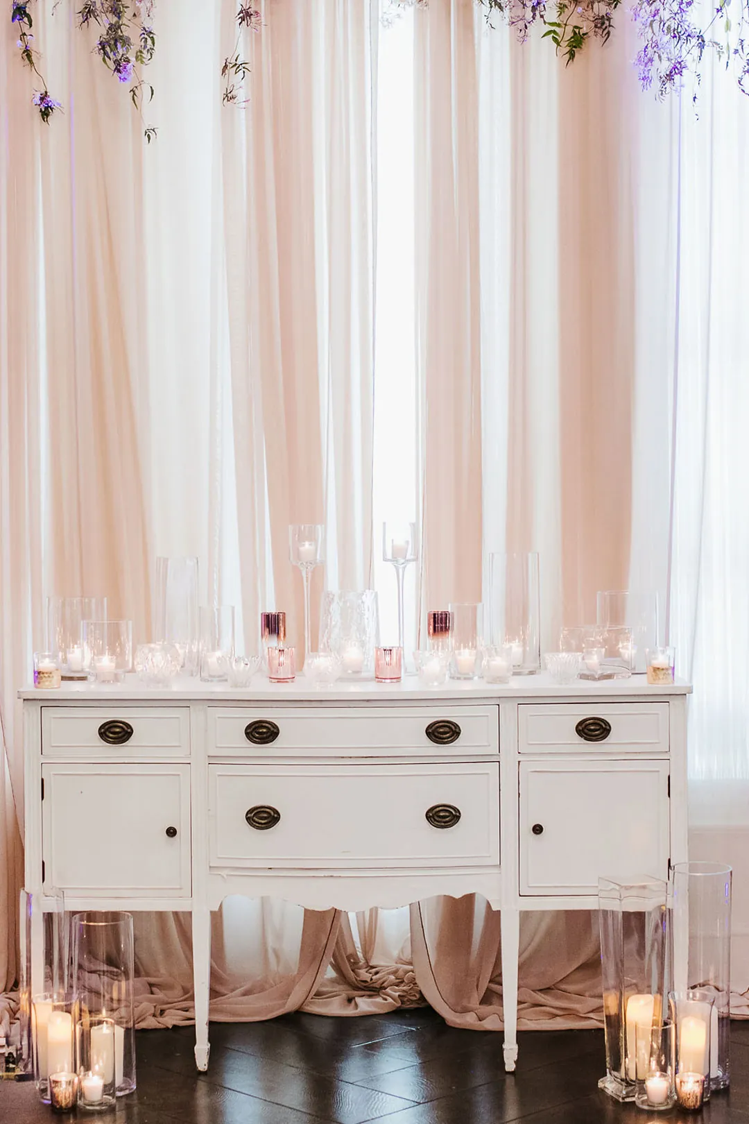 White drawers beneath a draped floral ceremony backdrop.