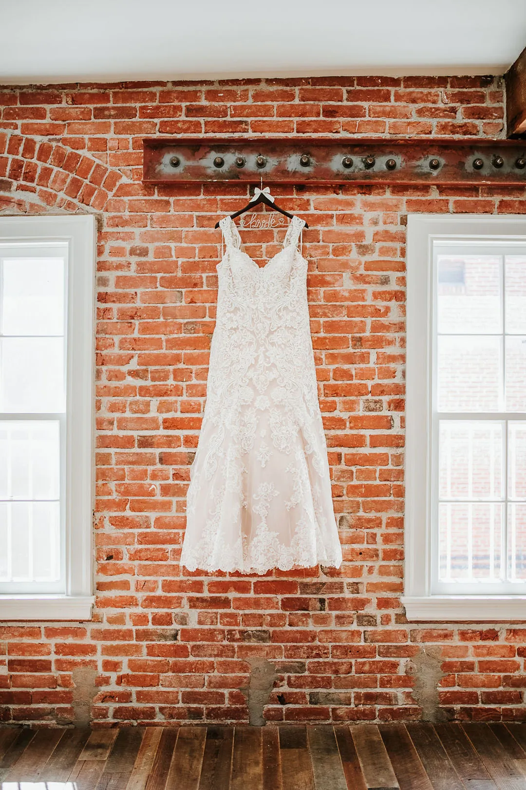 Wedding dress hangs against exposed brick.