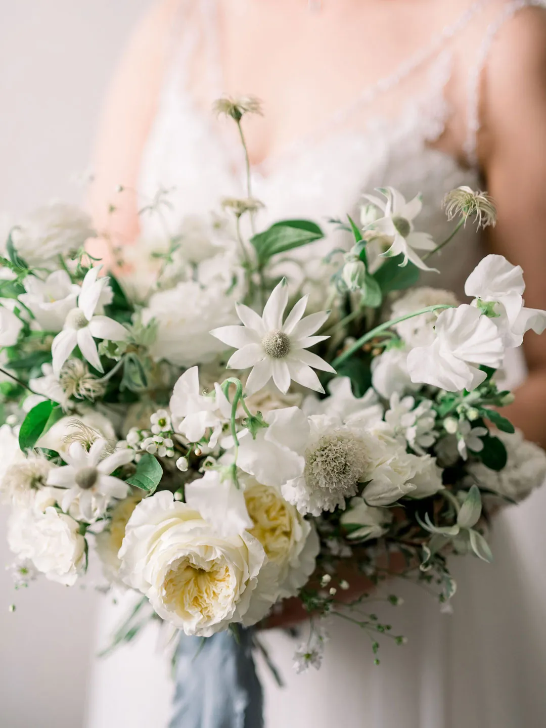 White bridal bouquet against a lace gown