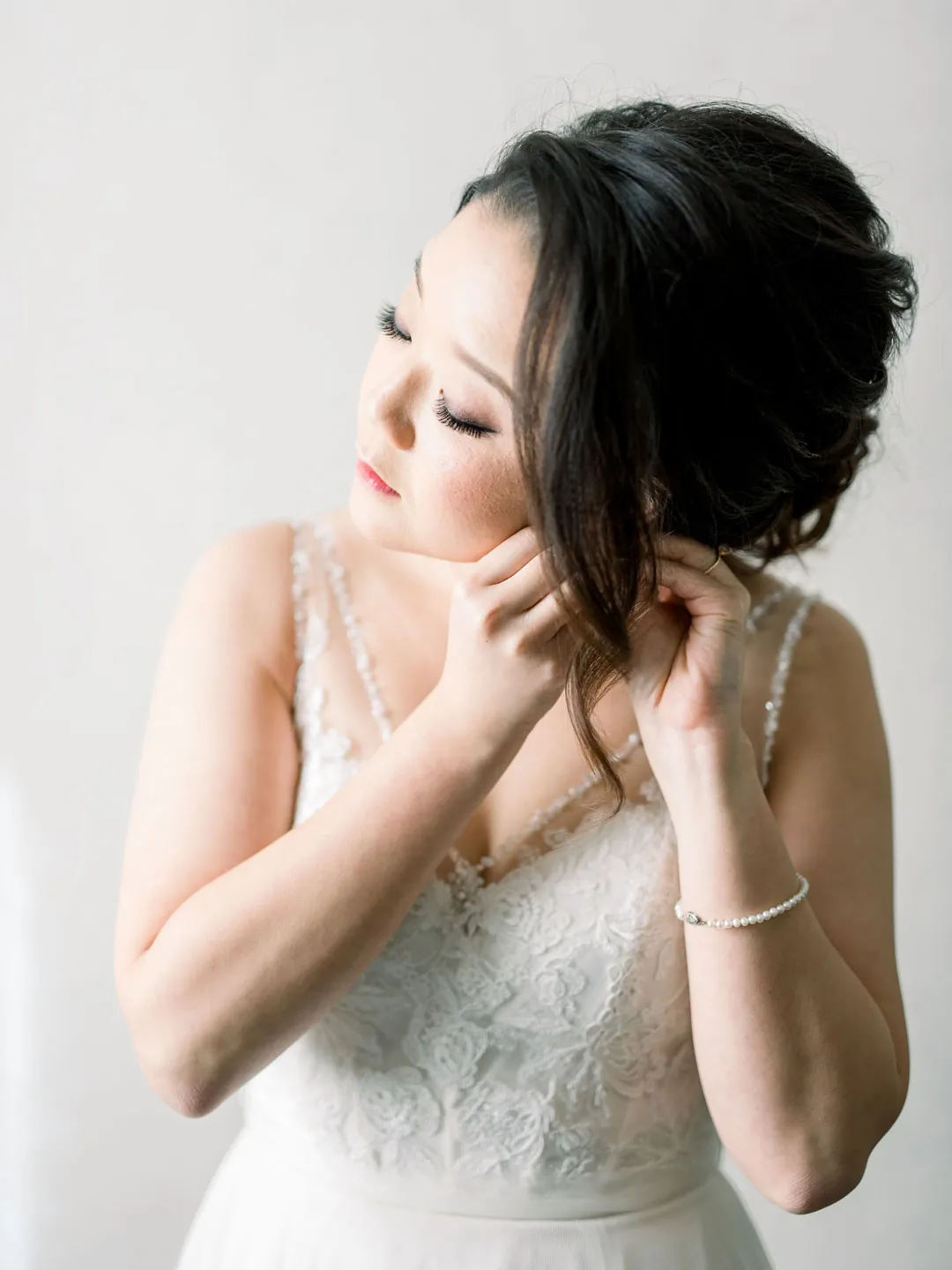 Bride putting on earrings by a window