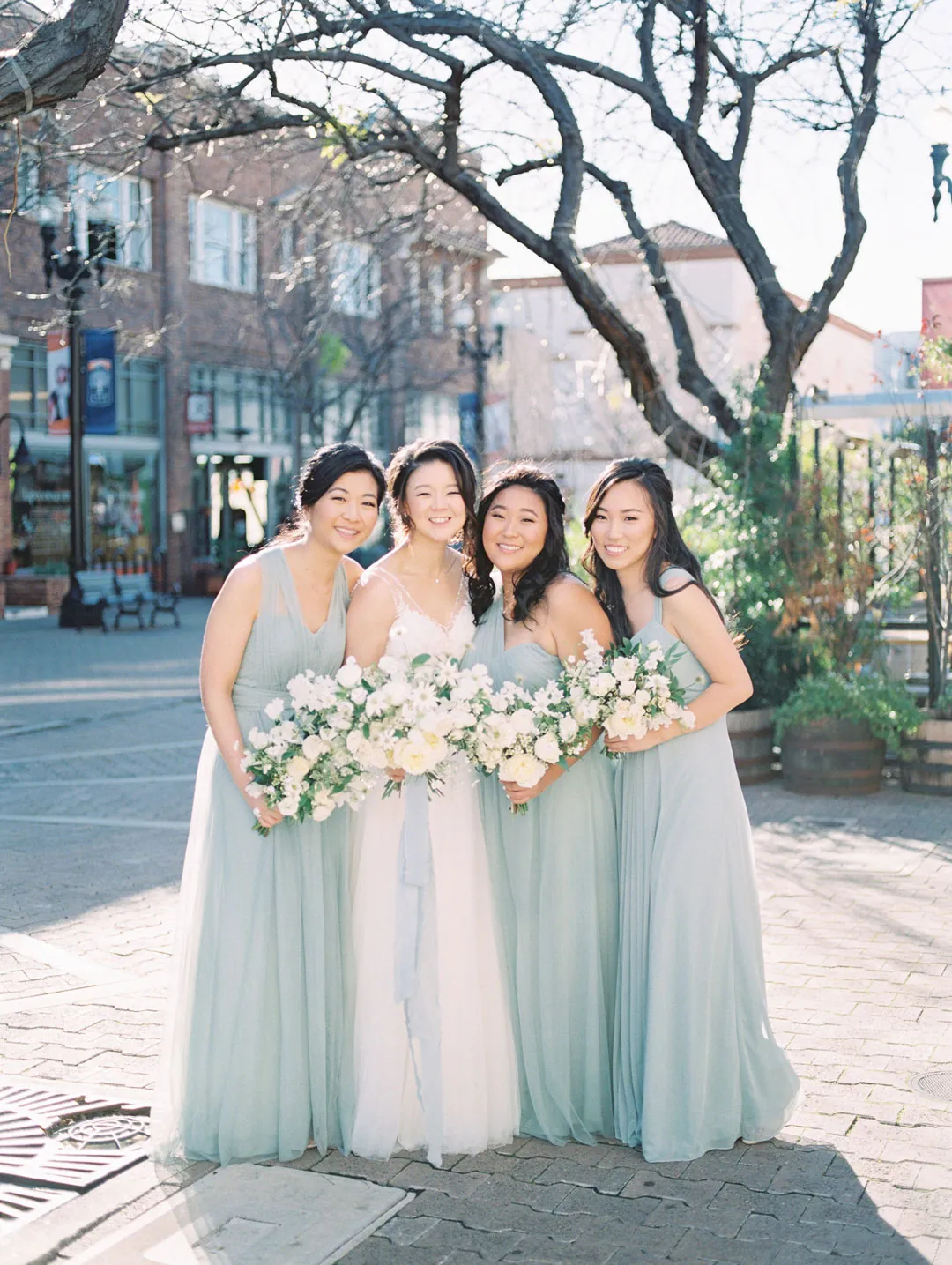 Bride and bridesmaids posing on a sidewalk