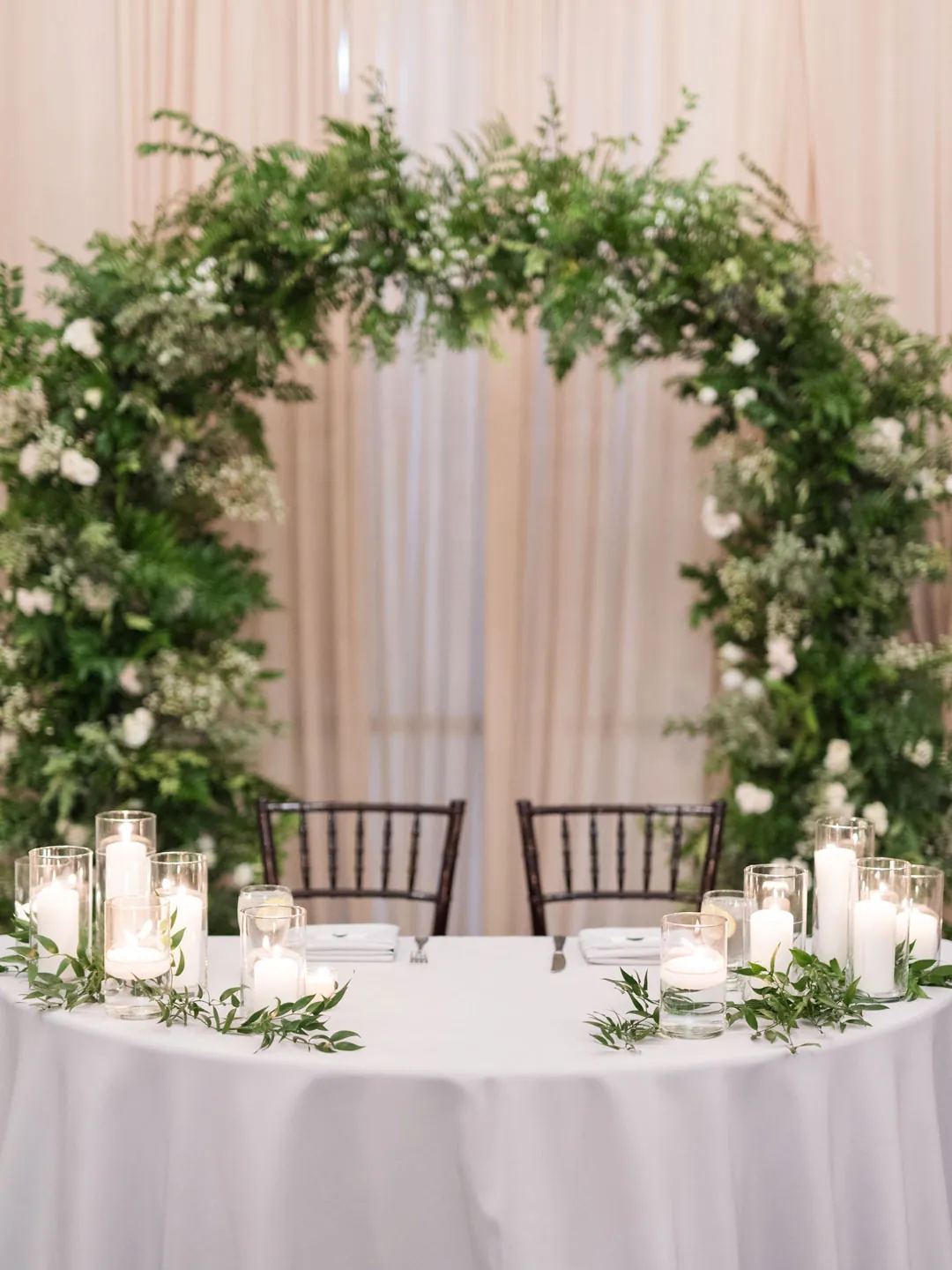 Round sweetheart table beneath a circular greenery arch
