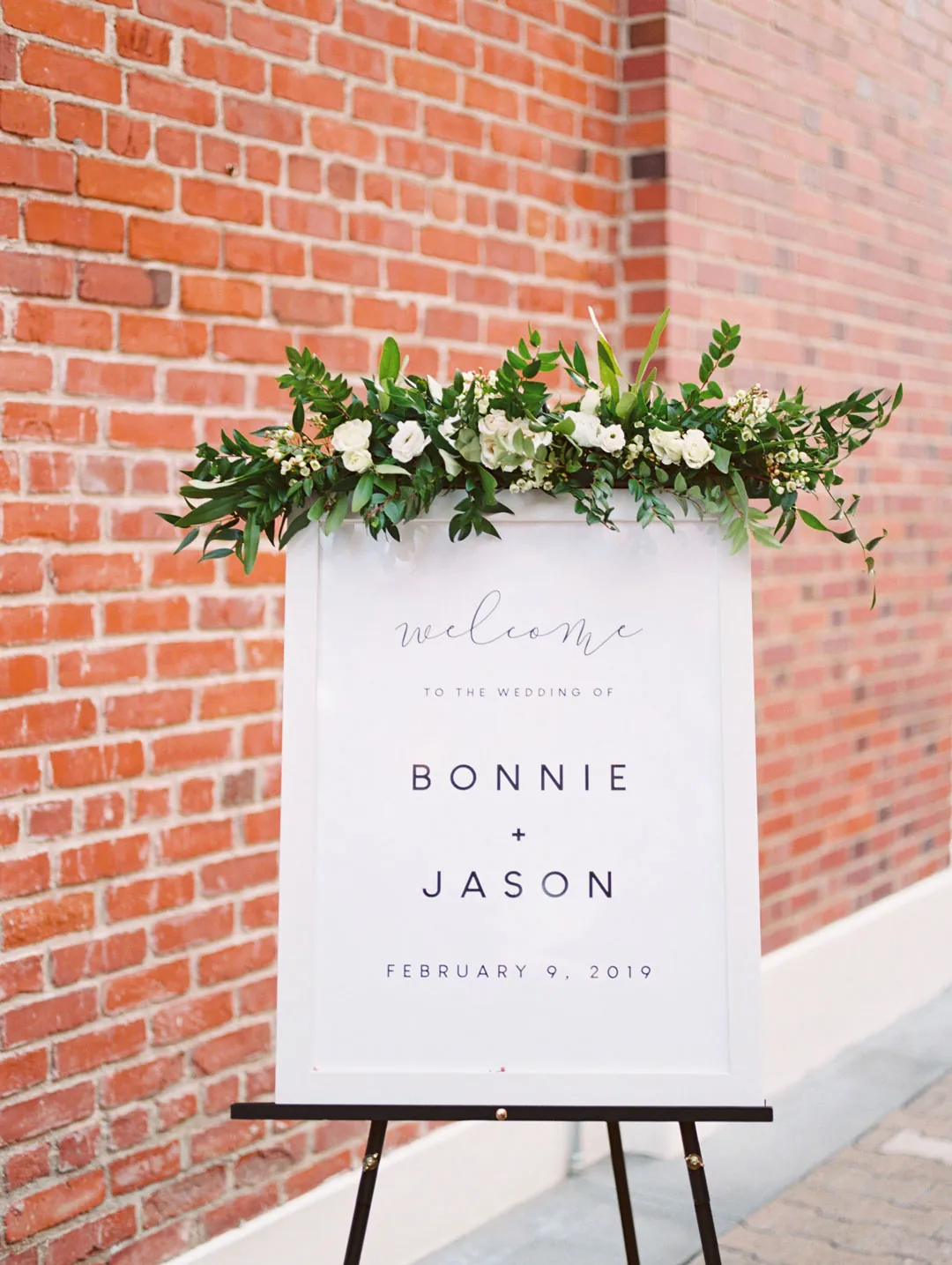 Wedding welcome sign topped with greenery