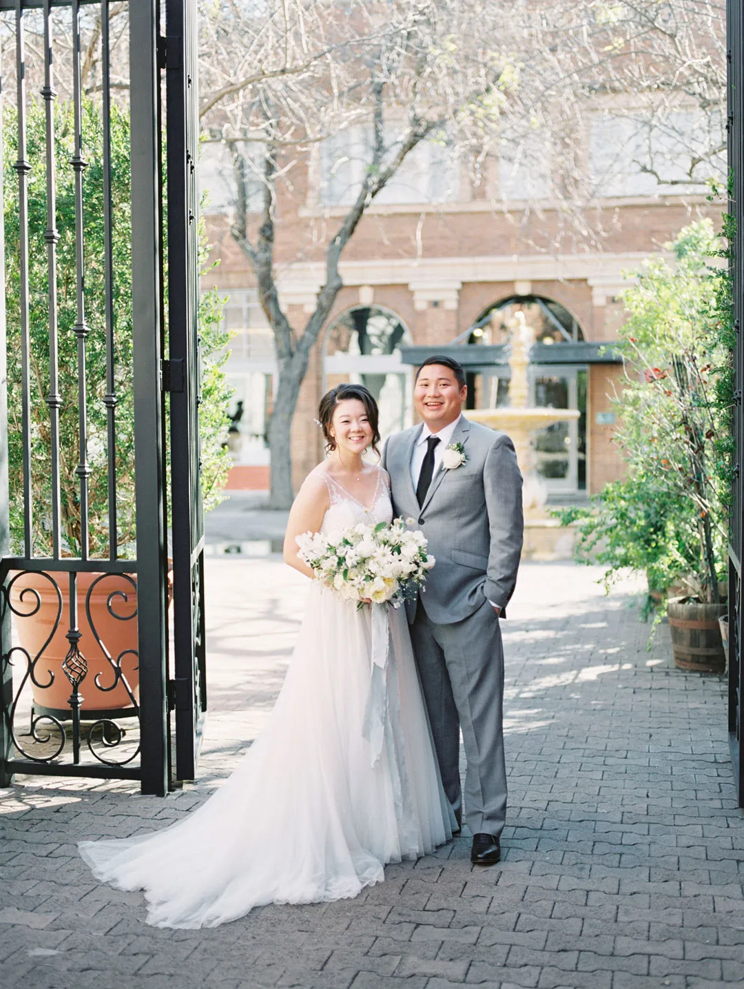Bride and groom posing beside the venue gate