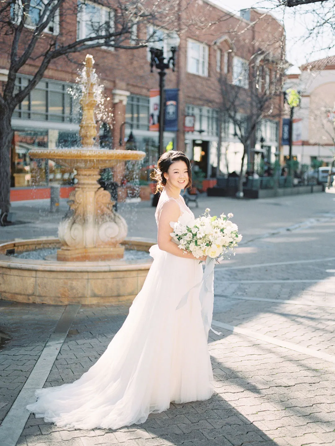 Bride standing beside an outdoor fountain
