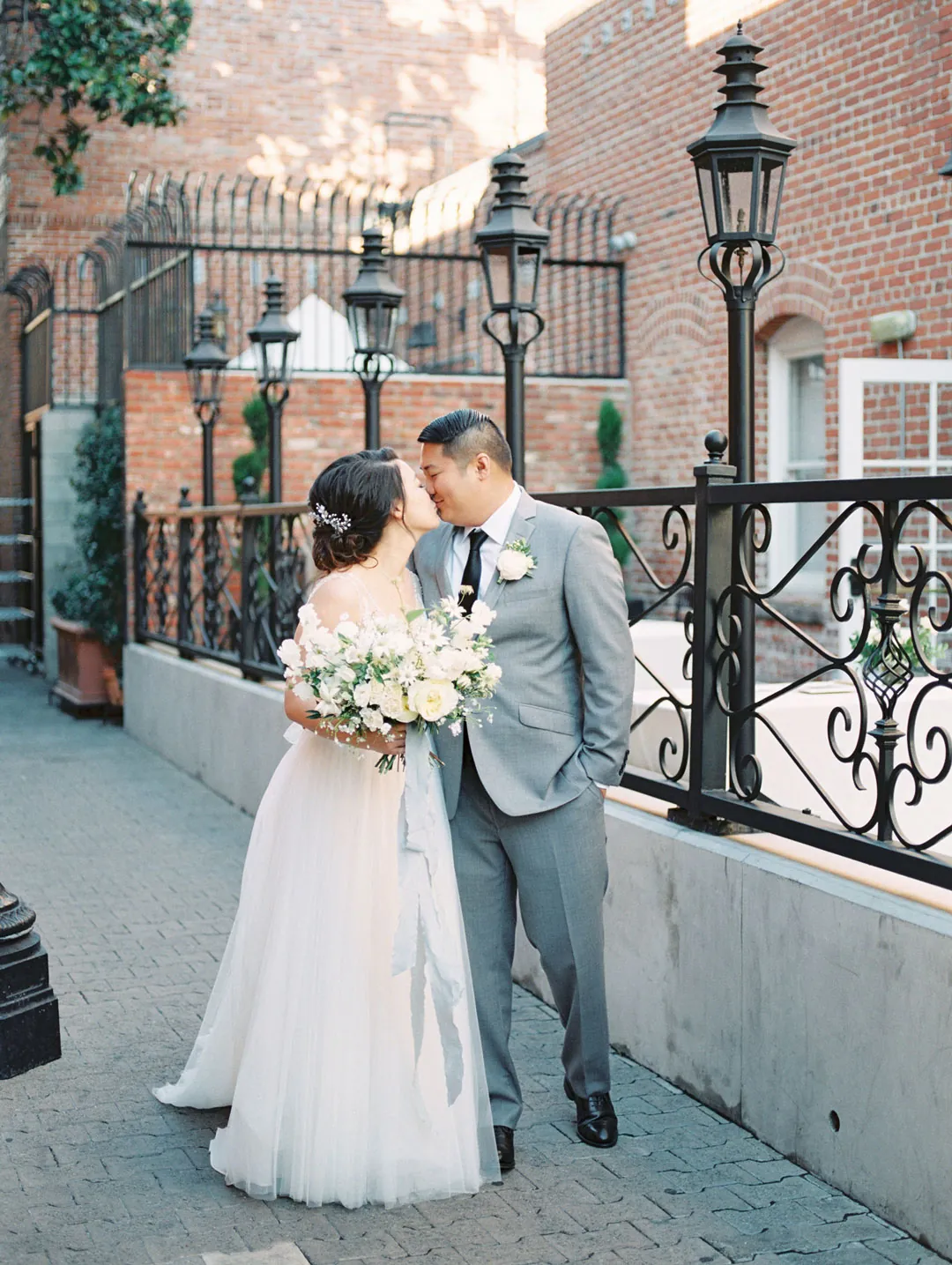Newlyweds embracing beside a wrought-iron railing