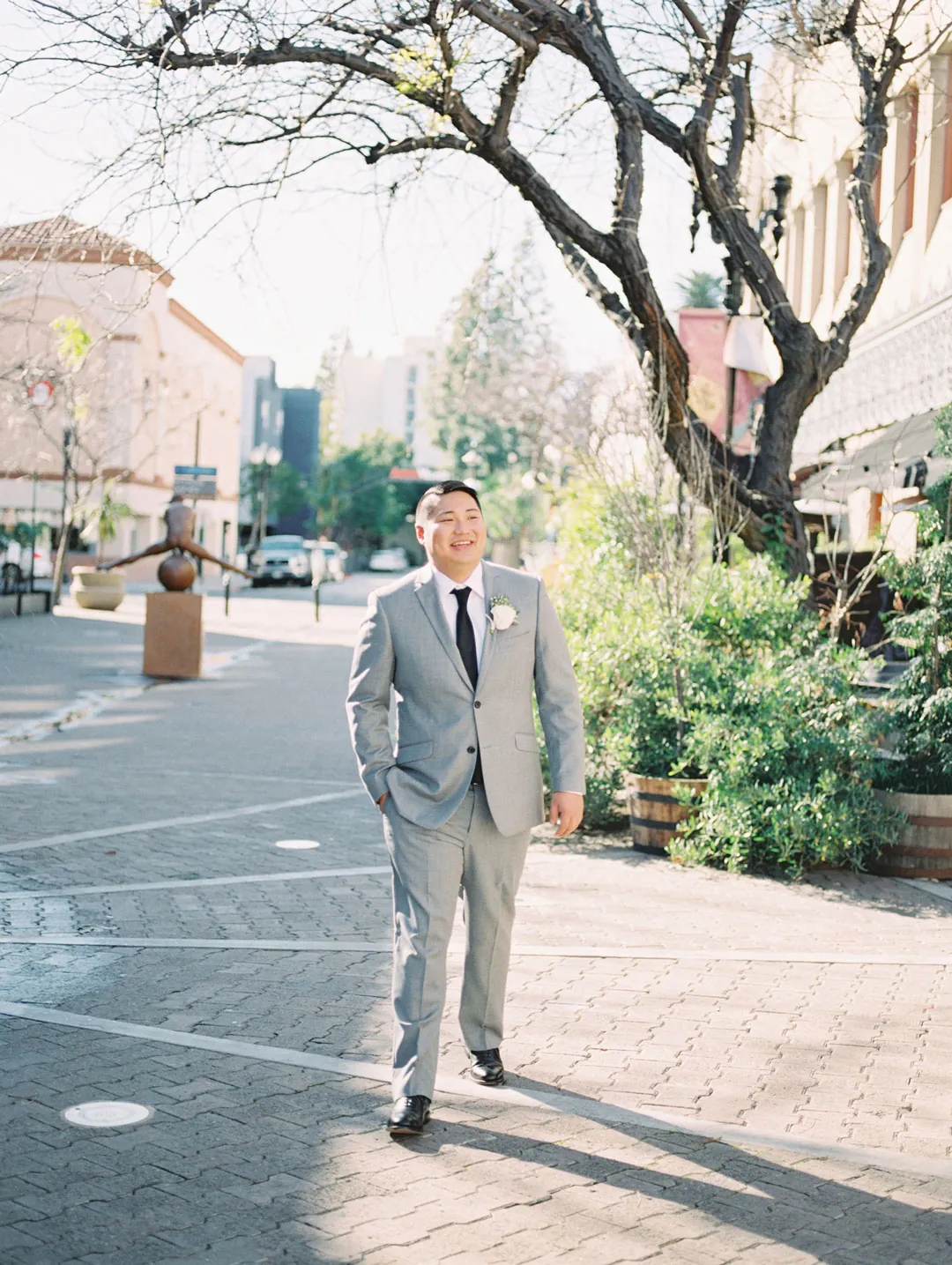 Groom posing in a gray suit outdoors
