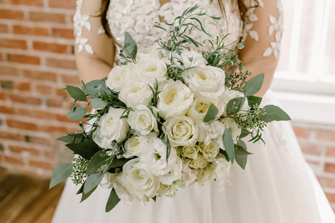 White bridal bouquet held against a wedding gown